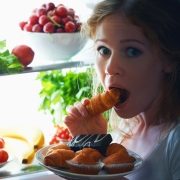 41607652 – woman eats sweets at night to sneak in a refrigerator
